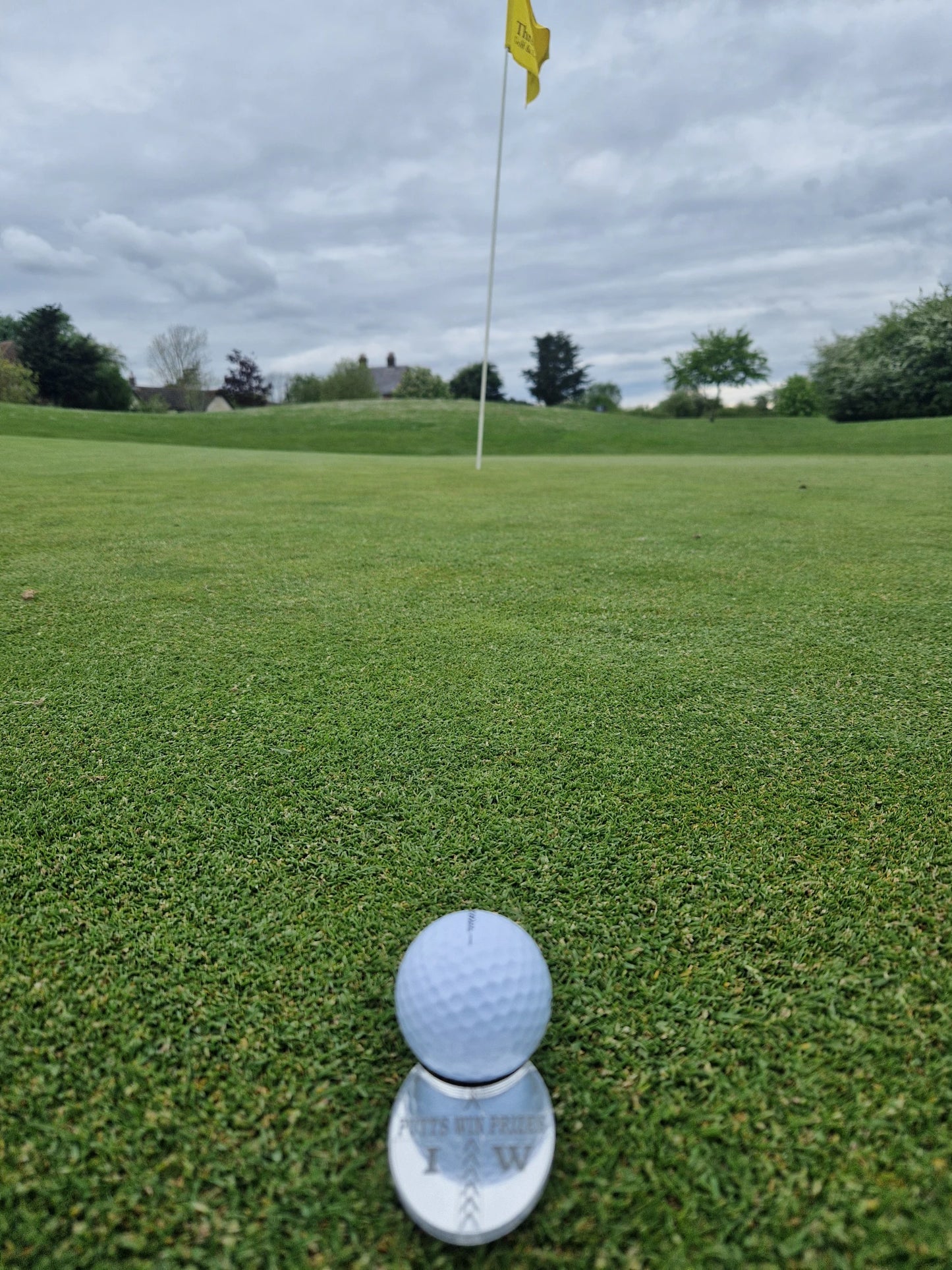 Sliver golf ball marker alignment tool with the ball sitting in the ball cut out lined up to the hole/pin