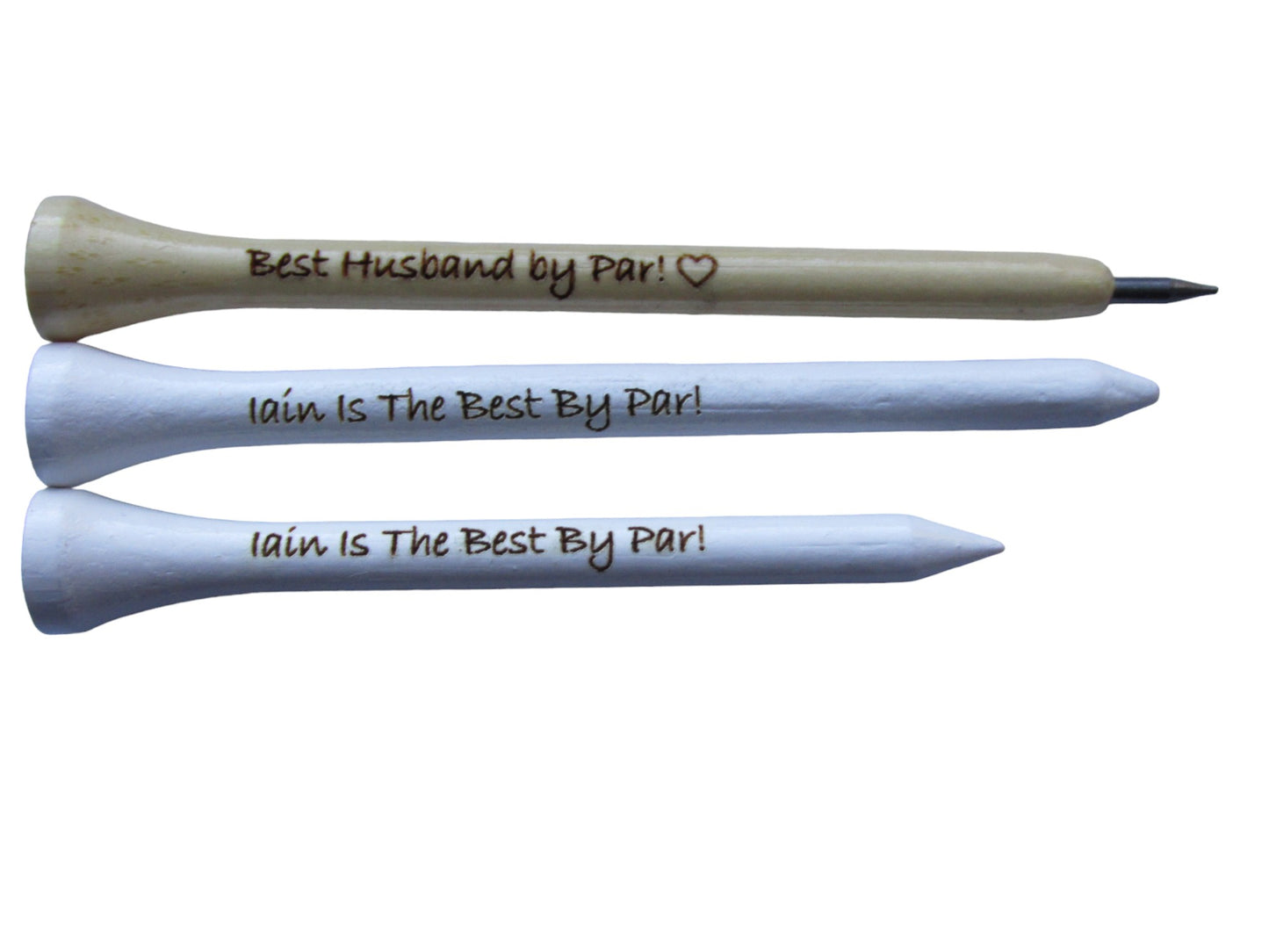 Natural pencil shaped like a golf tee with the text "Best Husband by Par!" and the outline of a heart engraved into it. A white 83mm tee with the text "Iain Is The Best By Par!" engraved into it and a 70mm white pencil with the text "Iain Is The Best By Par!" engraved into it.