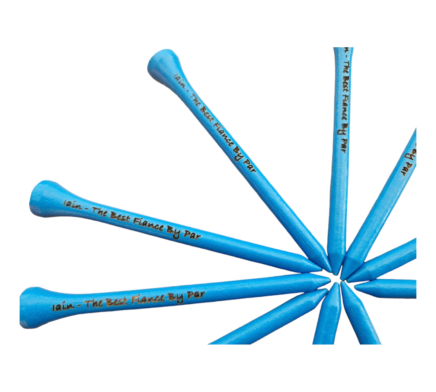 A close up of the blue golf tees with the text "Iain - The Best Fiance By Par" laser engraved into them