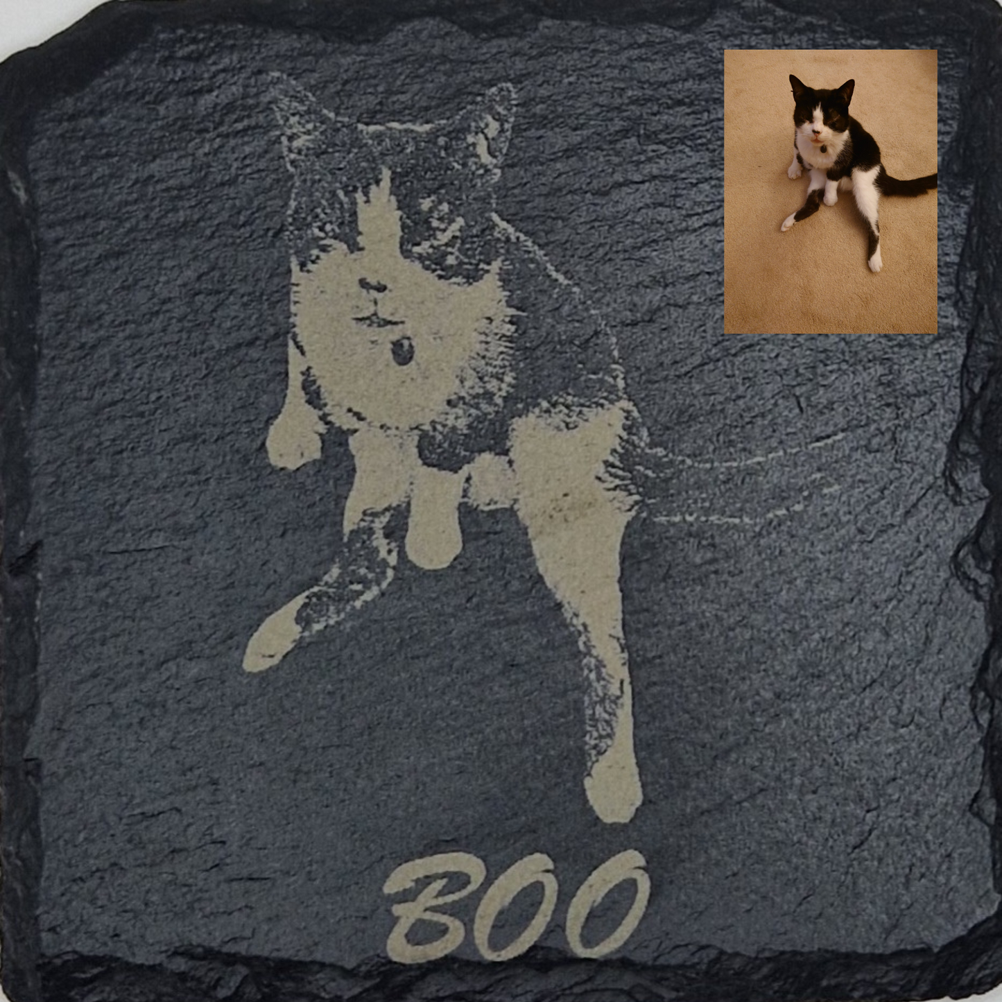 Slate coaster featuring the image of a cat laser engraved into it, with the text "Boo" written at the bottom in cursive text. In the top right corner there is a picture of the original image that was used, showing that the background has been removed.