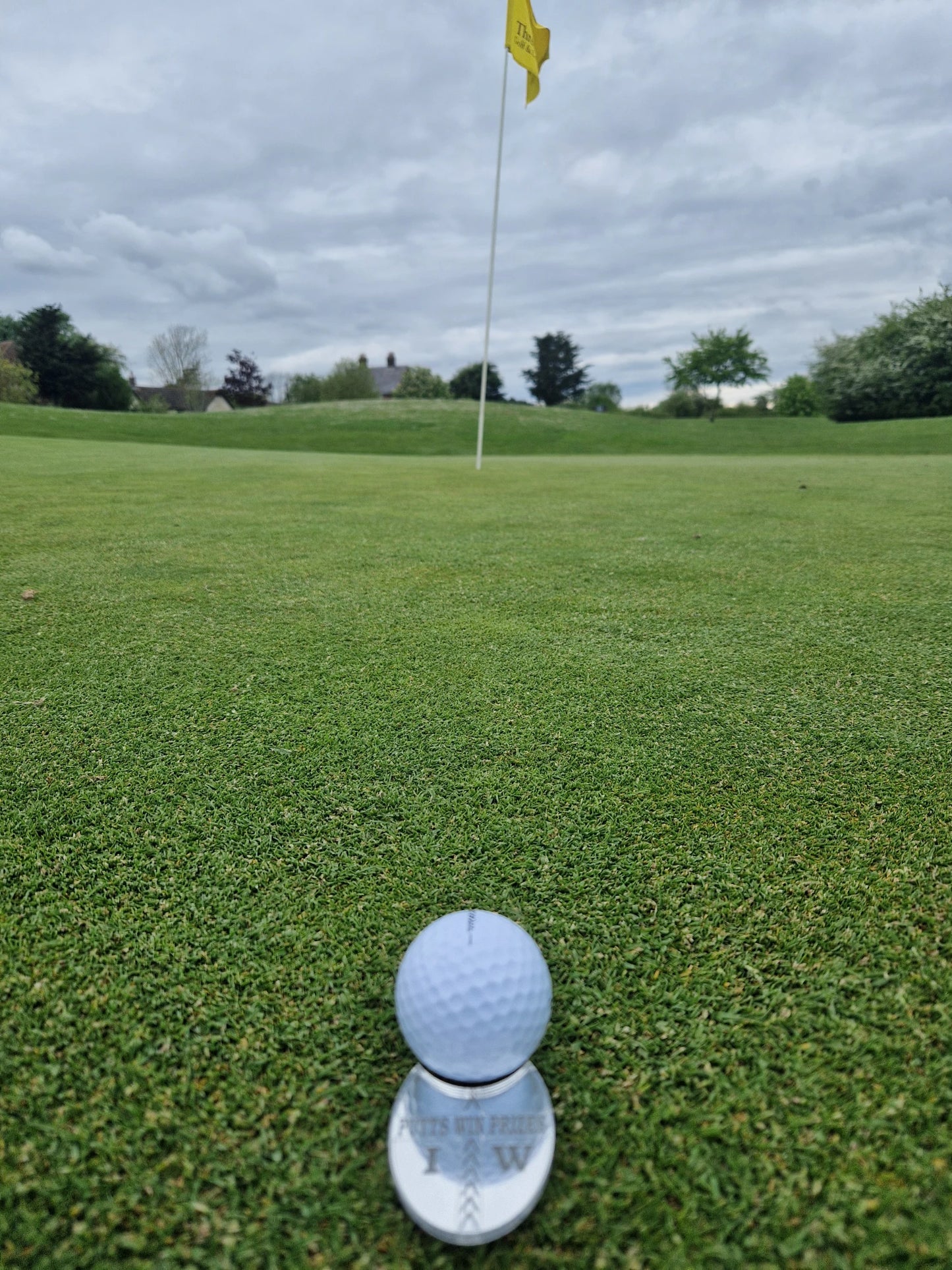 Sliver golf ball marker alignment tool with the ball sitting in the ball cut out lined up to the hole/pin