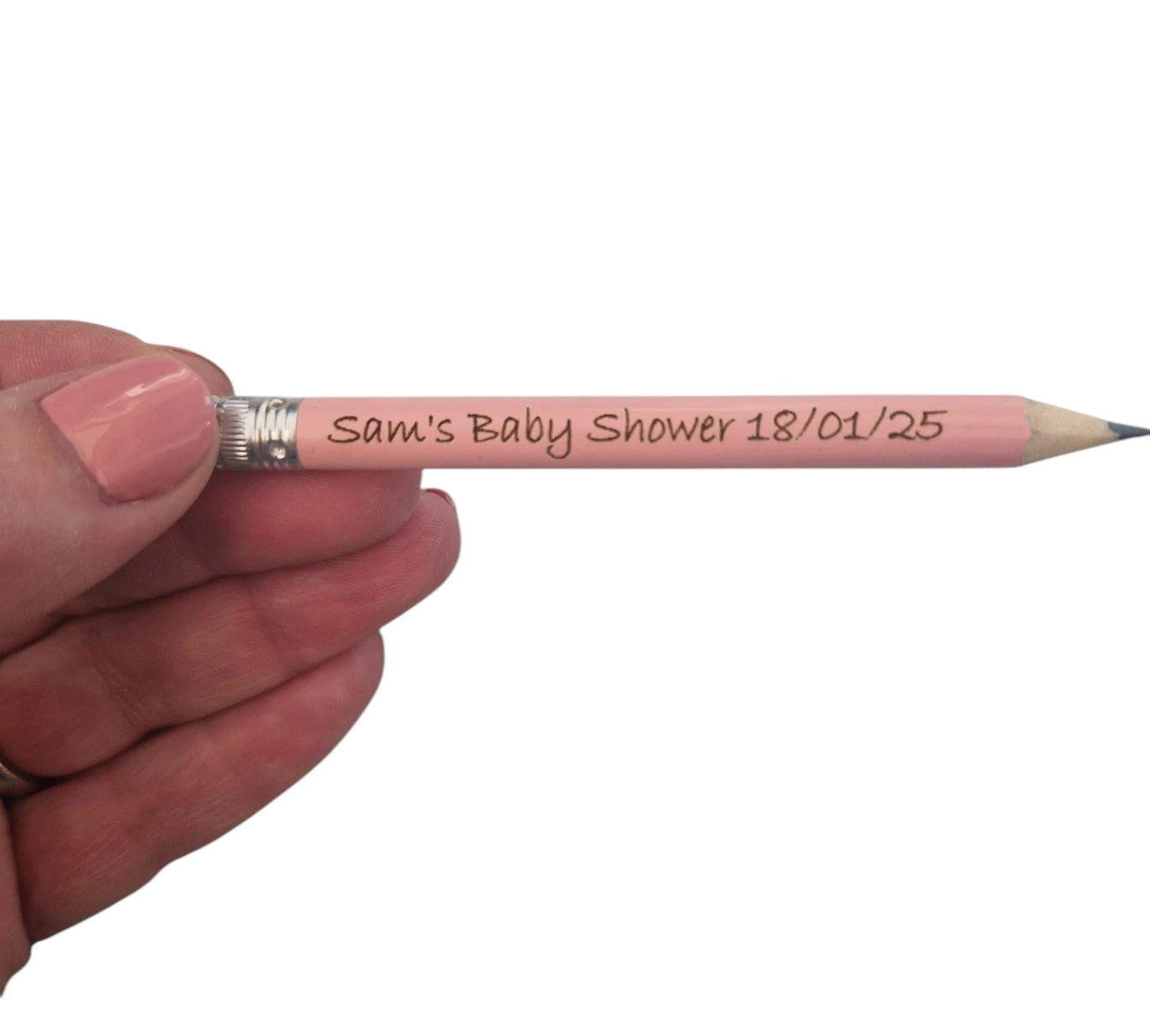 A hand holding a light pink mini pencil with the text "Sam's Baby Shower 18/01/25" laser engraved into it. 