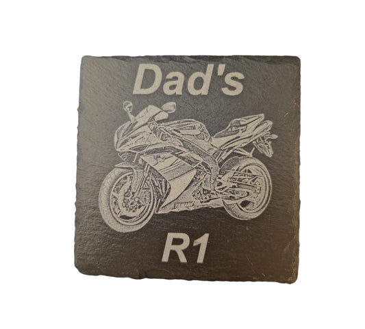 Square slate coaster with a motorbike laser engraved into the centre of the coaster. At the top of the coaster is the text "Dad's" at the bottom of the coaster is the text "R1".