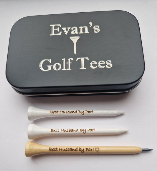 A black tin with the text "Evan's Golf Tees" and the image of a golf tee laser engraved into it. 2  white 70mm golf tees with the text "Best Husband By Par!" laser engraved into them and a wooden golf pencil shaped like a golf tee with the text "Best Husband by Par!" and the outline of a heart laser engraved into it. 