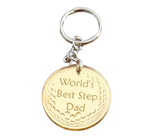 Gold mirror acrylic circle with the partial image of a golf ball with the text "World's Best Step Dad".  Attached to the circle is a metal keychain.