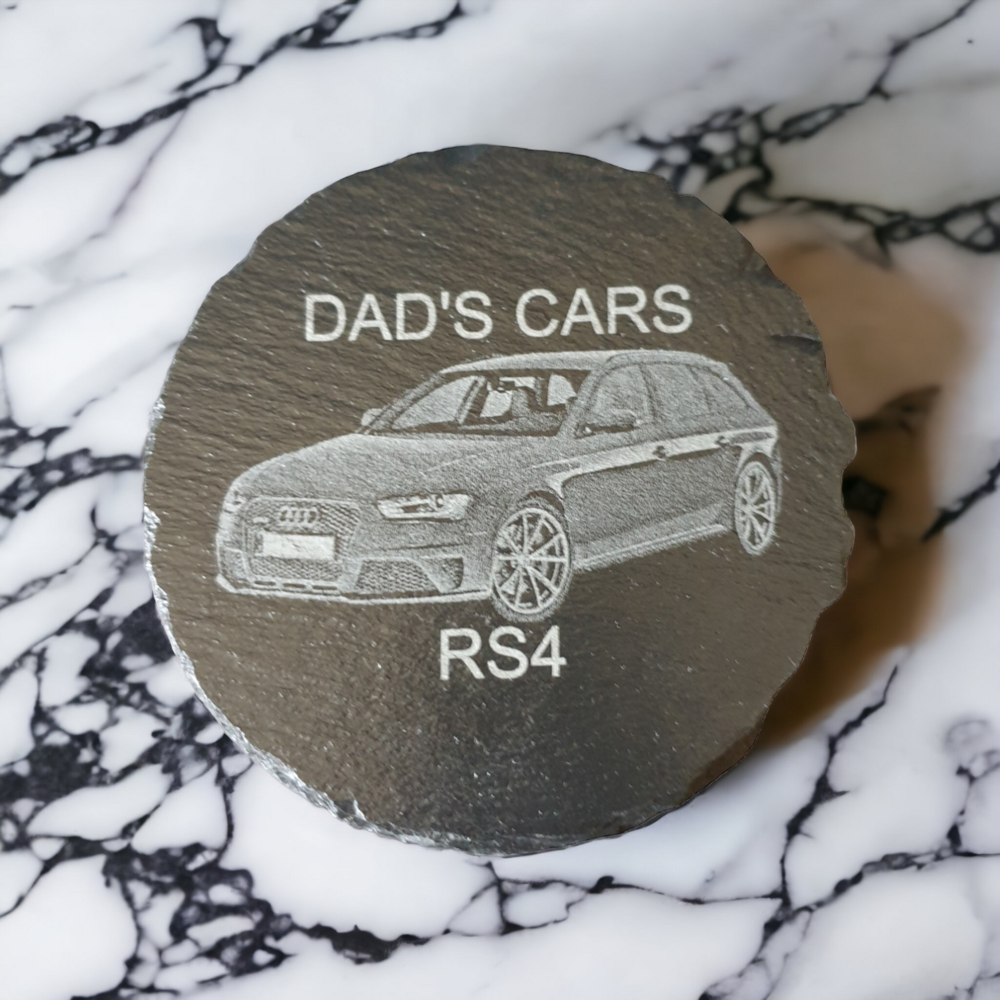 Slate personalised round coaster with the text "DAD'S CARS" at the top, "RS4" at the bottom and the image of an Audi RS4 laser engraved in the middle of the coaster